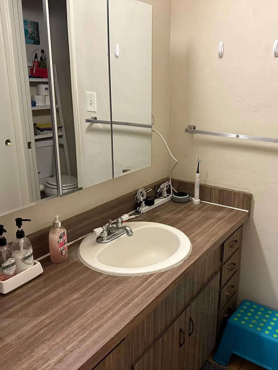 After: clean bathroom vanity with a clear counter, shiny sink and closed drawers