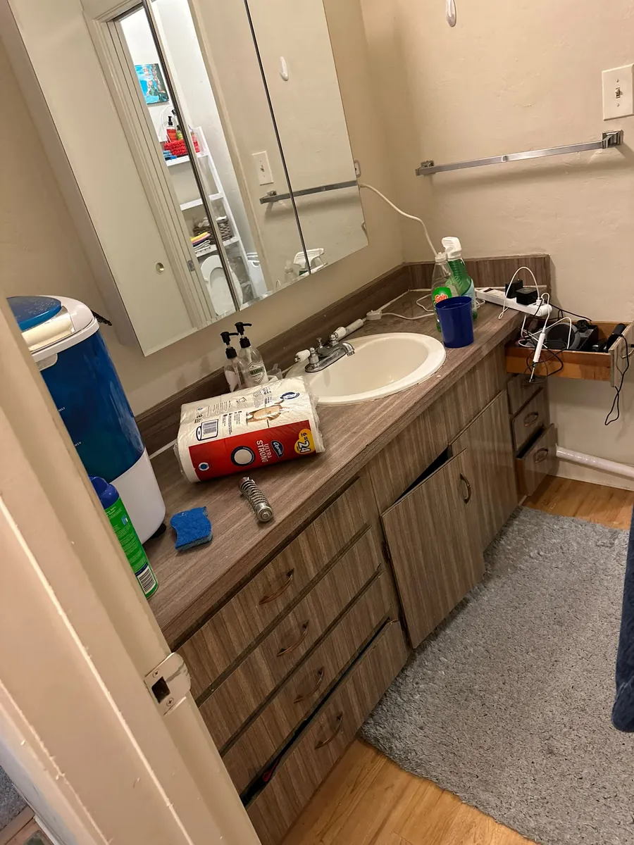 Before: bathroom vanity with supplies on the counter and drawers left open