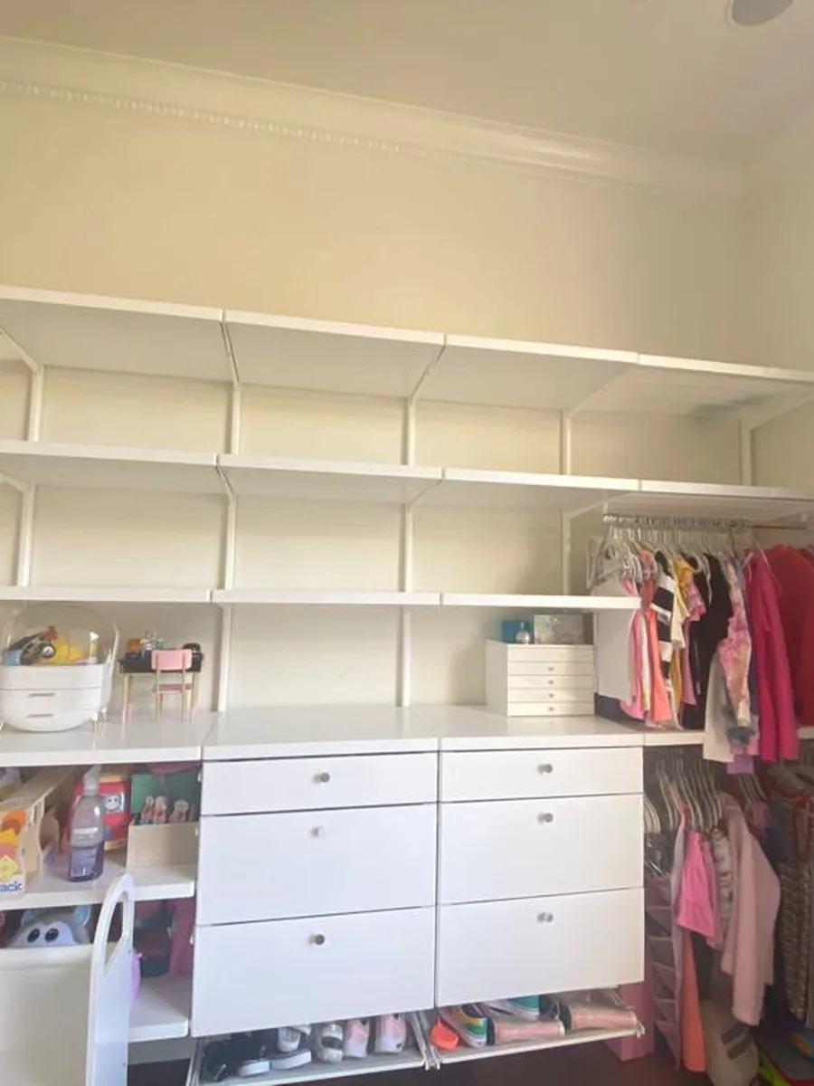 Before: kids' closet with bare white shelves, drawers and a hanging rod